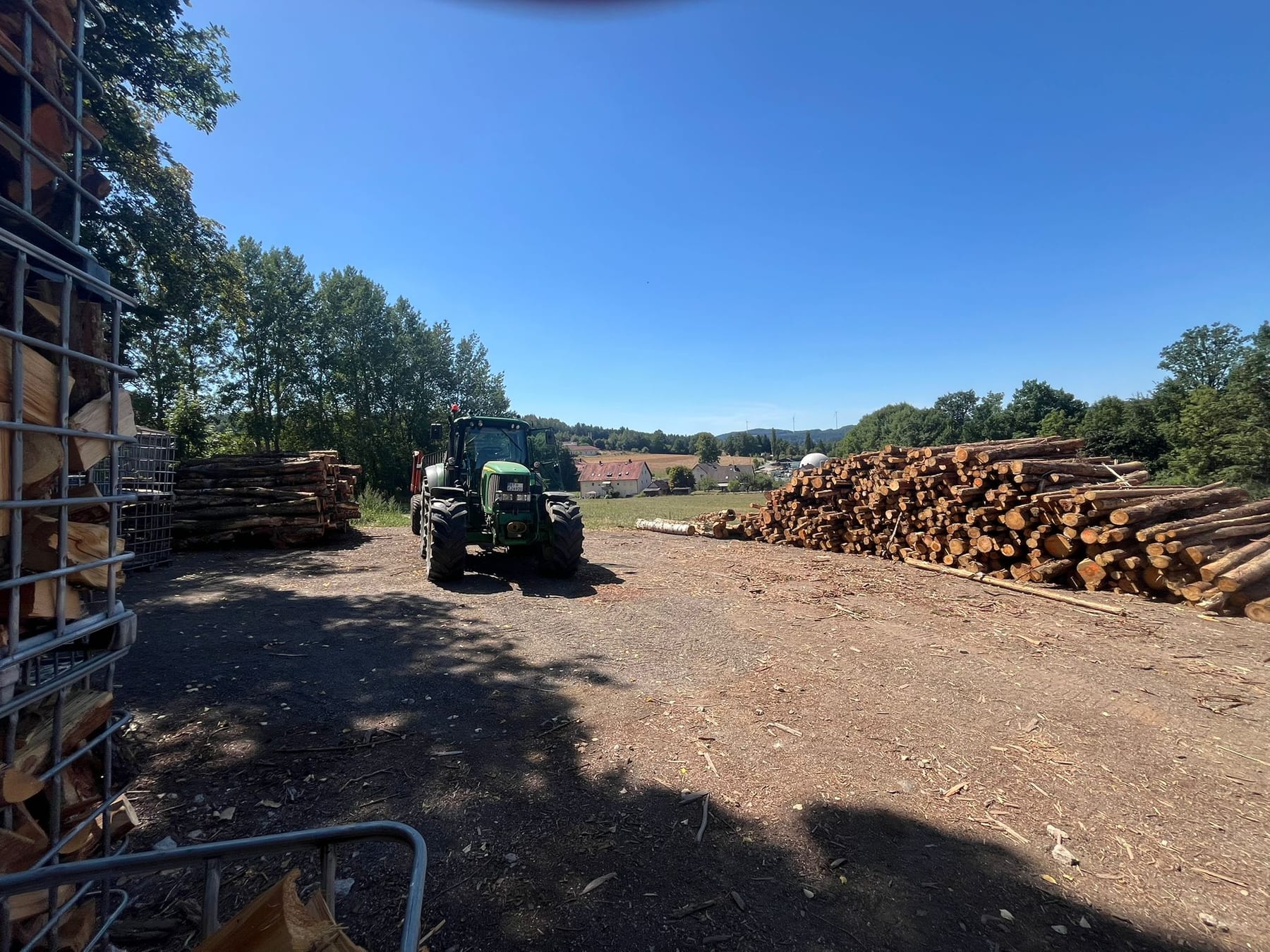 Der Holzplatz in Zips mit Traktor, Gitterboxen und Stammholzpolter